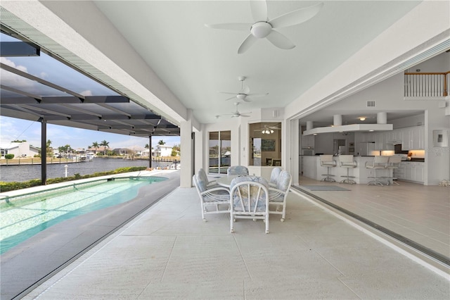 view of patio / terrace with ceiling fan, an outdoor bar, and a water view