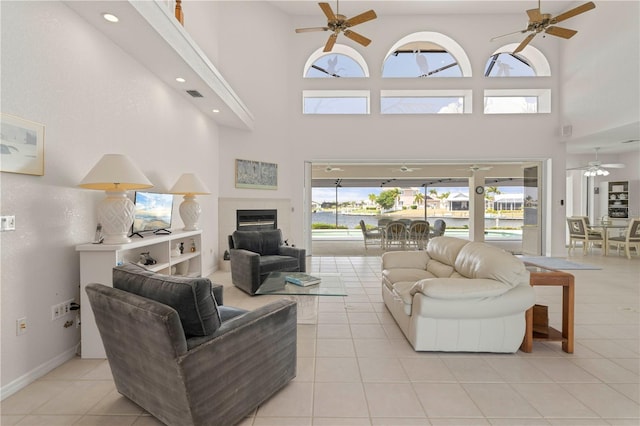 tiled living room with ceiling fan and a towering ceiling