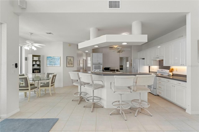 kitchen with white appliances, a kitchen island, white cabinetry, sink, and ceiling fan