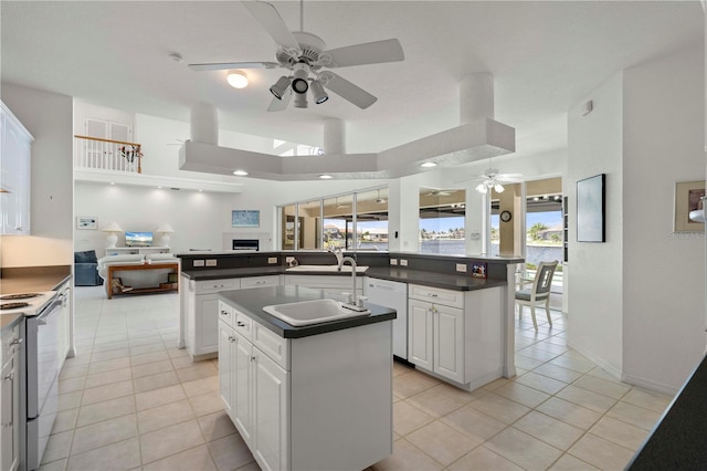 kitchen with white appliances, a center island with sink, white cabinets, and sink