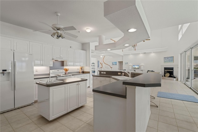 kitchen featuring white cabinets, a kitchen island, white appliances, and sink