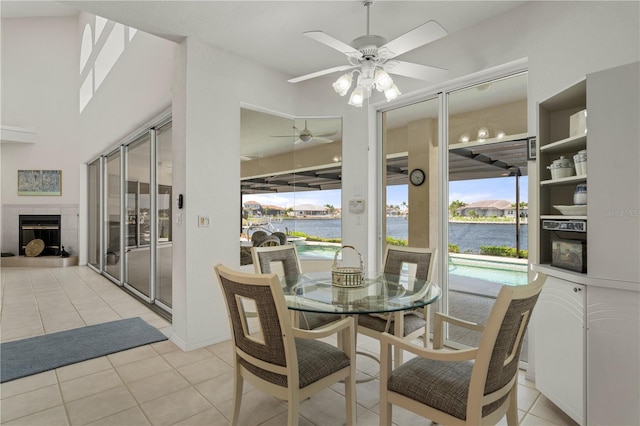 tiled dining room featuring a tiled fireplace and a water view