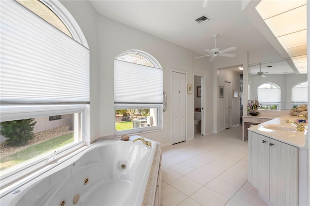 bathroom featuring toilet, tiled bath, tile patterned flooring, vanity, and ceiling fan