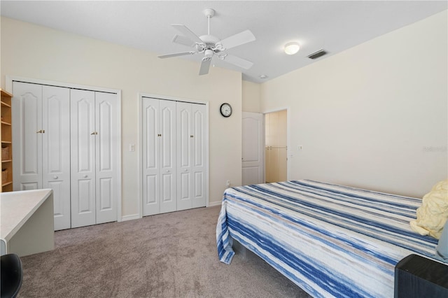 bedroom with ceiling fan, light carpet, and multiple closets