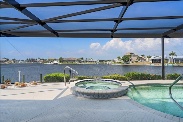 view of swimming pool with an in ground hot tub, a water view, a lanai, and a patio area