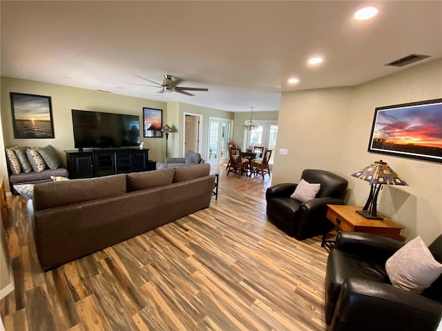 living room featuring wood-type flooring and ceiling fan with notable chandelier