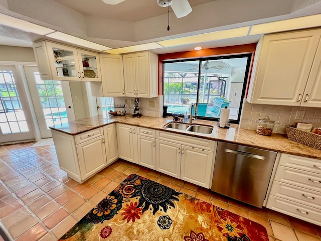 kitchen with light stone countertops, ceiling fan, tasteful backsplash, stainless steel dishwasher, and sink