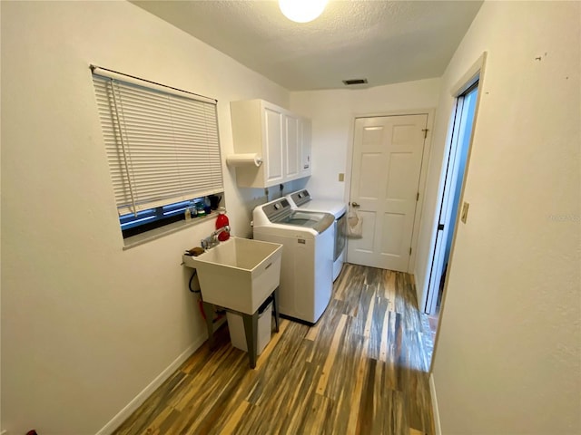 laundry room featuring sink, washing machine and clothes dryer, hardwood / wood-style flooring, and cabinets