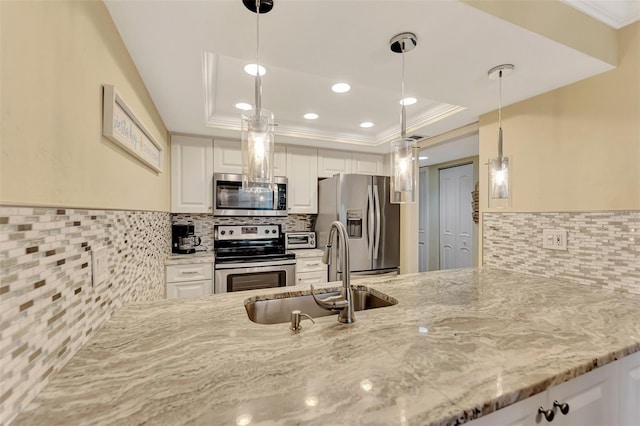 kitchen featuring white cabinets, decorative light fixtures, stainless steel appliances, sink, and a tray ceiling