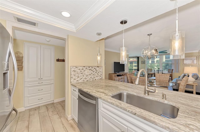 kitchen featuring stainless steel appliances, a notable chandelier, decorative light fixtures, light stone counters, and sink