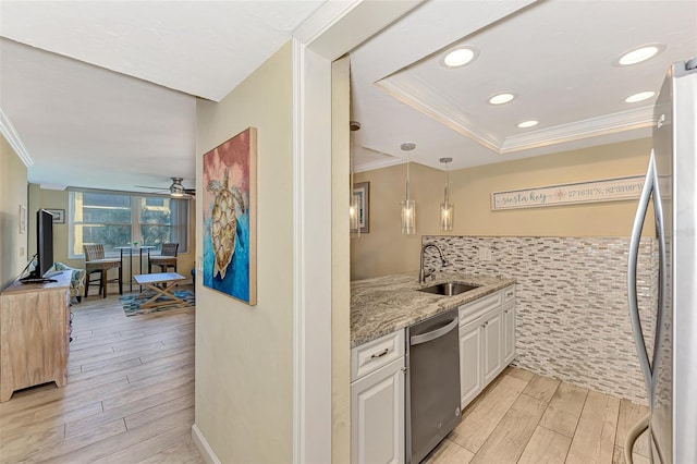 kitchen with light hardwood / wood-style floors, appliances with stainless steel finishes, decorative light fixtures, white cabinets, and sink