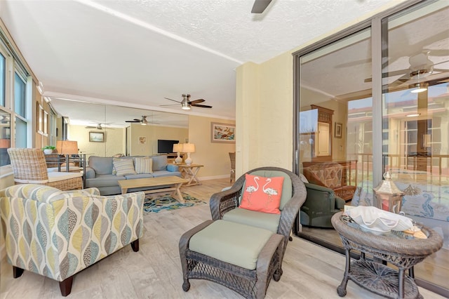 living room featuring ceiling fan, light wood-type flooring, crown molding, and a textured ceiling