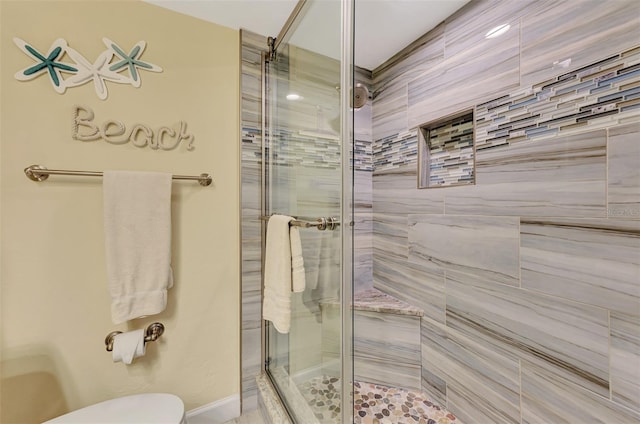 bathroom featuring toilet and a shower with door