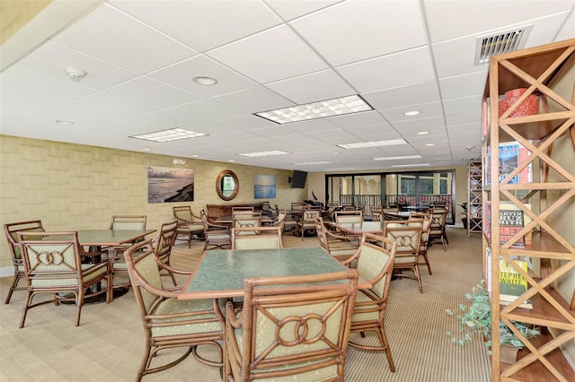 carpeted dining space featuring a drop ceiling