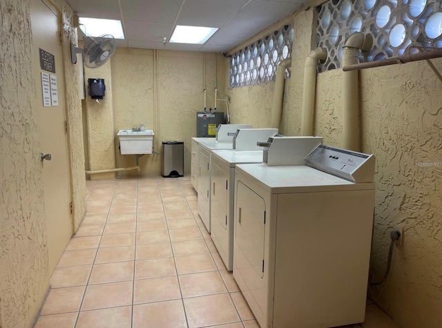 washroom with washing machine and dryer, light tile patterned floors, electric water heater, and sink