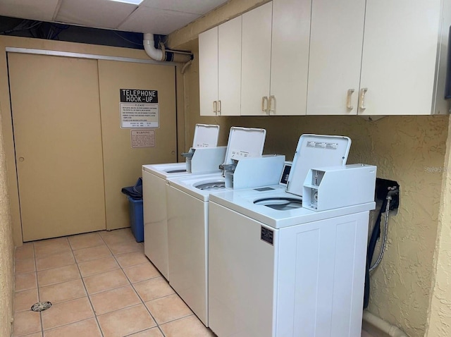 laundry room with light tile patterned floors, washer and dryer, and cabinets