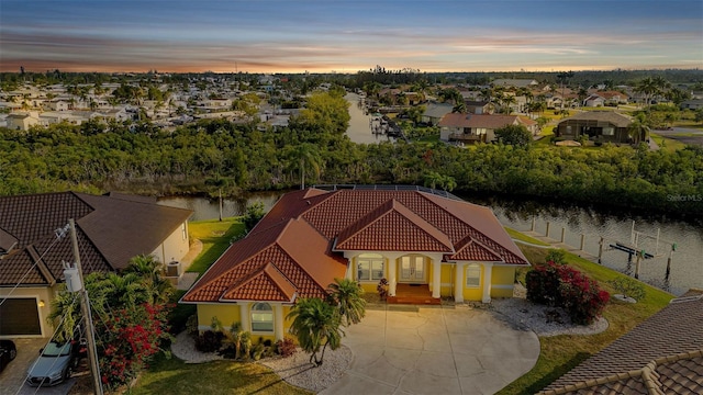 aerial view at dusk featuring a water view