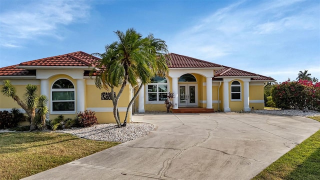 mediterranean / spanish-style house featuring a front lawn and french doors