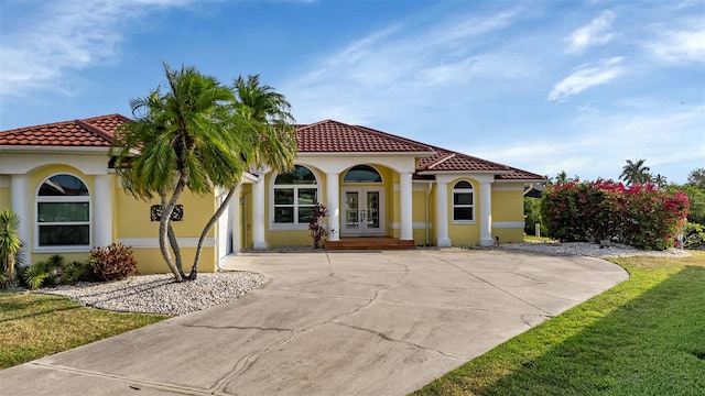 mediterranean / spanish-style home with a front yard and french doors