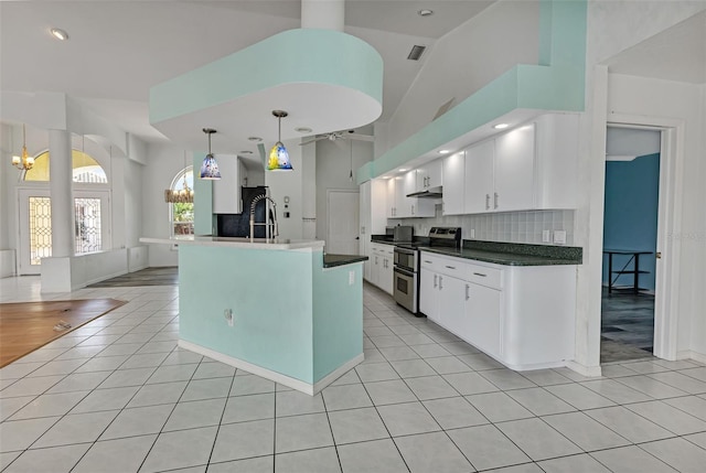 kitchen featuring tasteful backsplash, range with two ovens, light tile floors, hanging light fixtures, and white cabinets