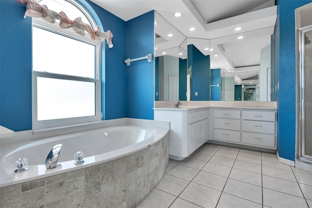 bathroom featuring a relaxing tiled bath, vanity, and tile floors