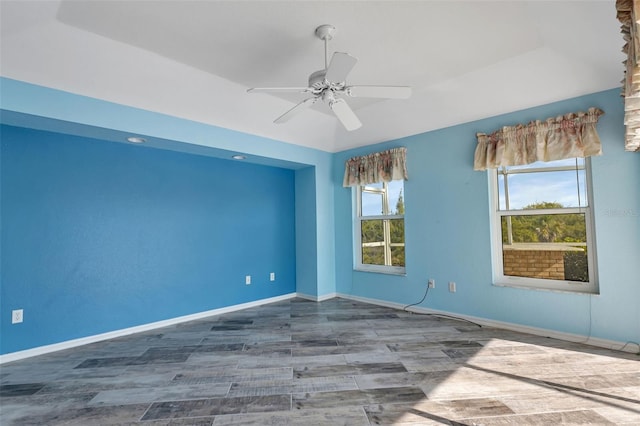 empty room with ceiling fan and a raised ceiling