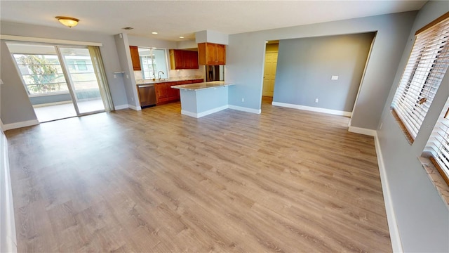 kitchen featuring stainless steel dishwasher, kitchen peninsula, sink, and light hardwood / wood-style flooring