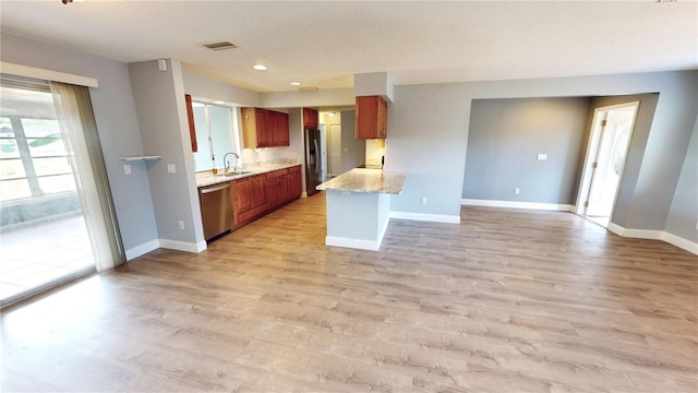 kitchen with a textured ceiling, light stone countertops, light hardwood / wood-style flooring, appliances with stainless steel finishes, and sink