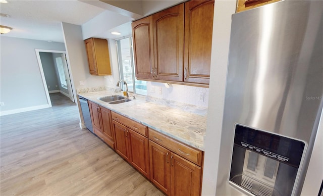 kitchen with stainless steel appliances, sink, light stone countertops, and light wood-type flooring