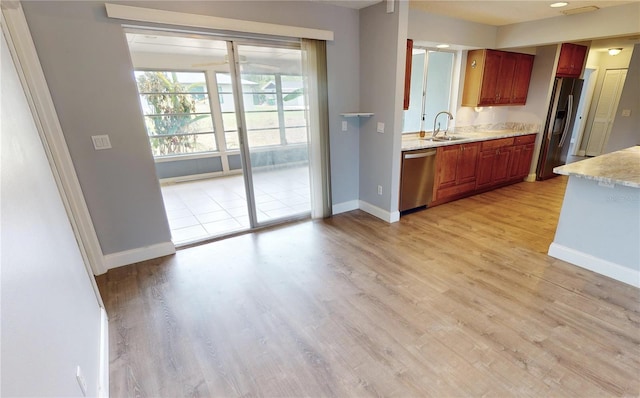 kitchen featuring light stone counters, stainless steel appliances, sink, and light wood-type flooring