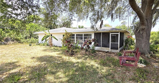 rear view of house featuring a yard and a sunroom