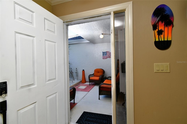 corridor with a textured ceiling and crown molding