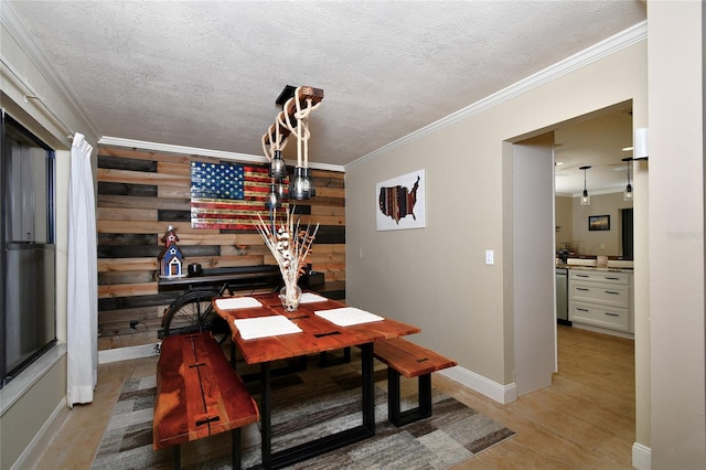 dining area featuring light hardwood / wood-style floors, a textured ceiling, ornamental molding, and wooden walls