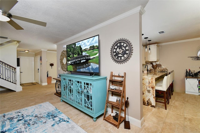 tiled living room featuring ornamental molding, ceiling fan, and a textured ceiling