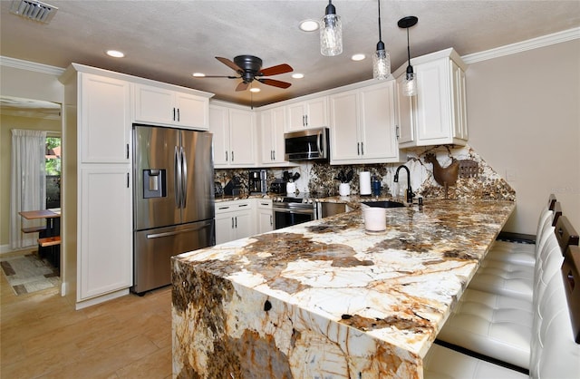 kitchen with white cabinets, appliances with stainless steel finishes, pendant lighting, and kitchen peninsula