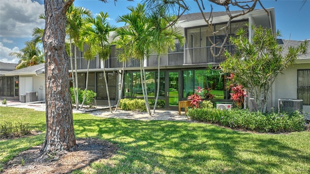 rear view of property featuring a lawn and central air condition unit