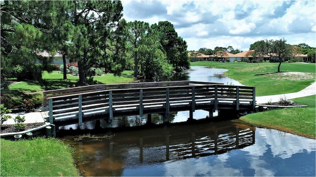 view of dock with a lawn and a water view