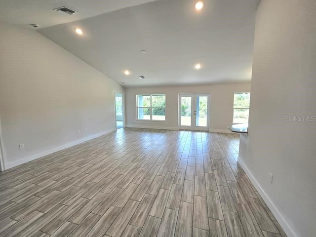 unfurnished room featuring vaulted ceiling, french doors, and light hardwood / wood-style flooring