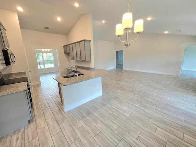 kitchen featuring light stone counters, stove, hanging light fixtures, sink, and vaulted ceiling