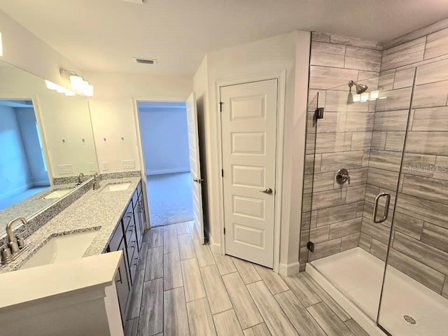 bathroom featuring a shower with shower door and vanity