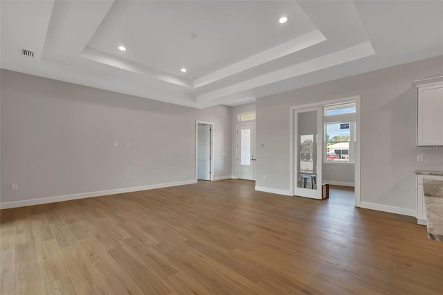 unfurnished living room featuring light hardwood / wood-style flooring and a tray ceiling