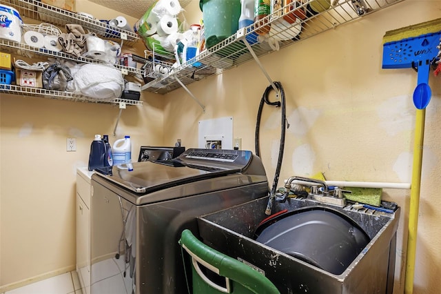 clothes washing area with sink, washing machine and dryer, and tile patterned flooring