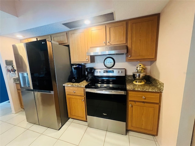 kitchen featuring appliances with stainless steel finishes, dark stone counters, and light tile patterned floors