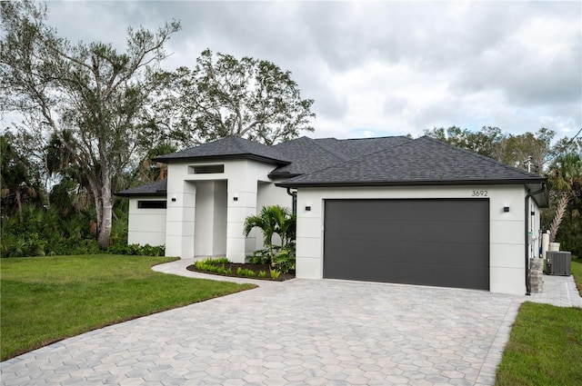 view of front facade with a garage, central air condition unit, and a front lawn