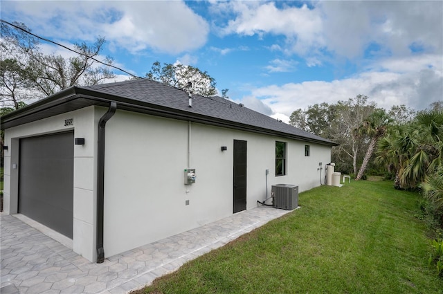 back of property with a garage, central AC unit, and a yard