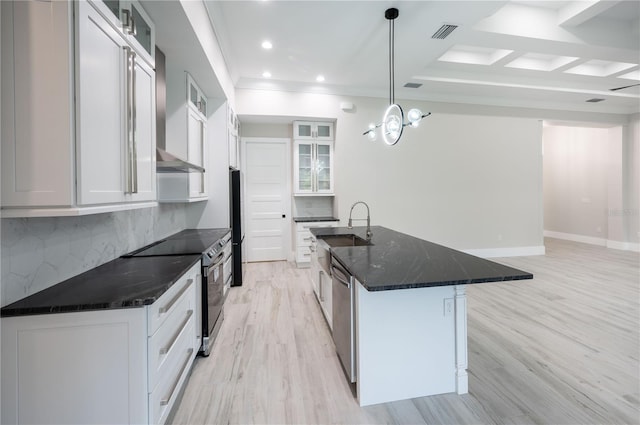 kitchen with stainless steel appliances, light hardwood / wood-style flooring, a center island with sink, and tasteful backsplash