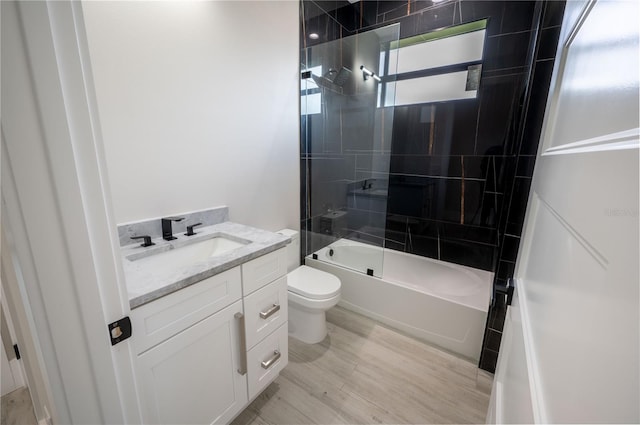 full bathroom with hardwood / wood-style flooring, tiled shower / bath combo, vanity, and toilet