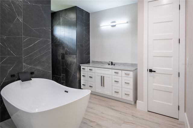 bathroom featuring wood-type flooring, tile walls, a bath, and vanity