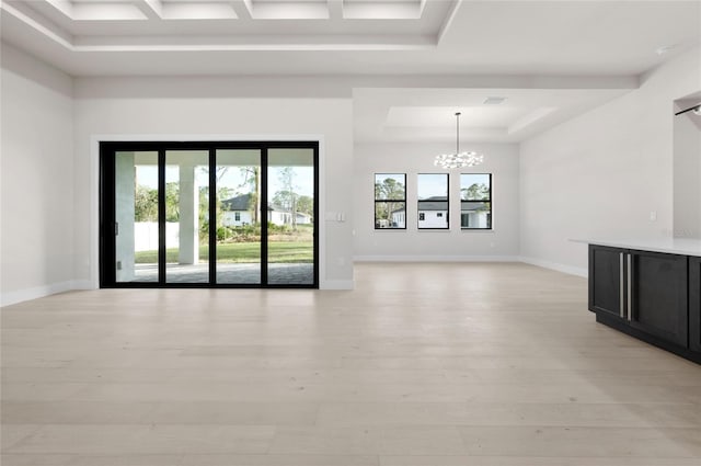 spare room featuring a chandelier, light hardwood / wood-style floors, and a tray ceiling