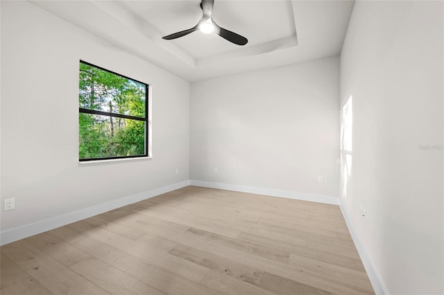 spare room featuring ceiling fan, a raised ceiling, and light hardwood / wood-style flooring